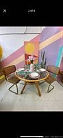 Front view of vintage bamboo table with glass top set with dining utensils and chairs in a colorful room.