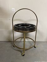 Full view of the mid-century bar cart on wheels showing the circular metal frame and handle.