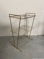 Side angle showing the three-level metal rack with tubular supports and slatted shelves