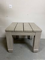Front view of the square outdoor patio table showing three slats and blocky legs.