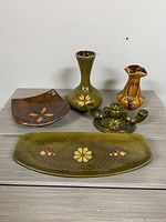 Full lot showing all five pottery pieces on table against white wall