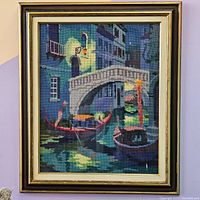 Full view of the framed vintage cross-stitch artwork depicting a Venetian canal scene with gondolas and an arch bridge.