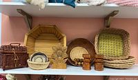 Shelf display of various wood and wicker items including baskets, trays, wooden candle holder, wooden salt and pepper shakers, and wooden bowl with nuts