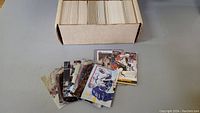 Box filled with thousands of mixed hockey cards in sleeves and loose cards displayed in front.