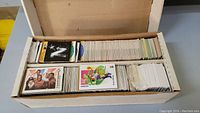Open box revealing large quantity of mixed sports and trading cards arranged in stacks.