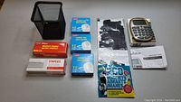 Overview of lot showing various stationery items including the mesh pen holder, calculator, staples, sticky tape, instruction booklet, and magnets.