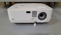 Front view of white NEC NP300 projector showing lens and ventilation grills with small crack on the lens area.