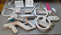 Full overview of assorted Nintendo Wii accessories laid out on a table showing controllers, attachments and charging docks.