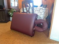 Portable massage table folded with removable headrest attached, reddish-brown vinyl upholstery visible, no visible damage.