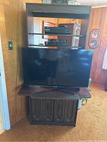 Front view of modified shelf/wall unit holding a 40-inch flat screen TV with electronic devices on upper shelves