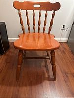 Front view of wooden chair showing spindle backrest and contoured seat.