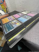 Side view of black binder filled with pages of Pokémon cards inside plastic sleeves