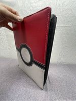Closed Pokémon-themed binder with Poké Ball design on cover held upright