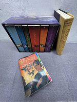 Photo showing six Harry Potter hardcover books in a purple slipbox labeled 'Harry Potter Complete Collection', with a hardcover titled 'Harry Potter and the Cursed Child' and a French language paperback book on the surface.