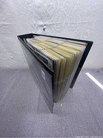 Black binder filled with pages of Pokémon cards viewed from an angle showing thickness.