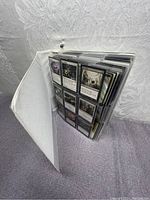Open white binder showing plastic sleeves filled with Magic: The Gathering cards.