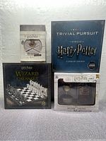 Photo of four Harry Potter branded items: Wizard Chess Set, Trivial Pursuit Ultimate Edition, Vinyl Figure with 3-Pack Socks, and a Hogwarts crest collectible display.