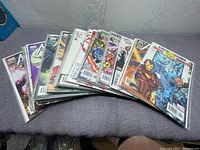 Photo showing a spread of 15 Avengers comic books fanned out, each in protective plastic cover, with covers featuring various Avengers characters.