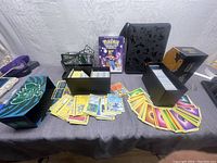Wide shot of Pokémon cards spread around with card boxes and binder on a table