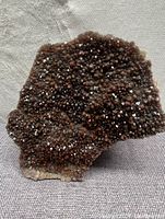 Front view showing the dense cluster of red and black amethyst crystals with sparkling surfaces on natural mineral base.