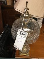 Full view of crystal clear glass lamp with brass base and attached tag labeled 'Crystal Lamp'