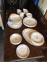 Overview photo of the mixed floral china set with various plates, bowls, and cups arranged on a wooden surface.