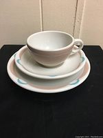 Photo showing a stack with a cup, small plate, and large plate all featuring the pink and blue pattern on heavy diner-style white china.