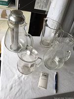 Top-down view of 4 clear glass pitchers including one with metal ice core inside, placed on white cloth
