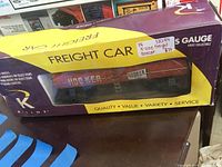 Front view of K-Line S Gauge Freight Car boxcar in original purple and yellow box showing HOOSIER branding through clear plastic window.