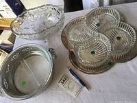 Silverplated oval tray with 4 divided glass serving dishes and oval cut glass bowl on a cloth-covered table with pen and note card