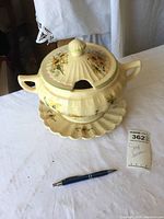 Full view of the ceramic soup tureen with floral designs, lid, and attached underplate.