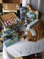 Overview photo showing poker set open with chips, Thomas toys in packaging, roller skates, wooden houses, baseball gloves, toy trucks, and stuffed horse