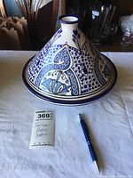 Full view of the Tunisian pottery cooker showing the conical shape and blue decorative patterns on white ceramic.