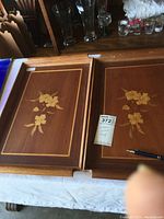 Two wooden trays with floral inlaid designs side by side, displaying the full trays and design details.