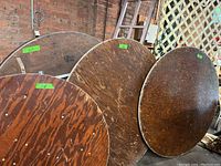 Four round wood topped folding catering tables with aluminum legs. Three tables are 60 inches in diameter and one is 48 inches in diameter. Tops show wear consistent with heavy use.
