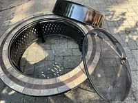 Top view showing the fire pit inner chamber, decorative tiled rim, and mesh cover partially removed.