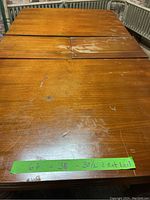 Top view of the solid oak dining table showing dimensions marked on a green tape: 67 x 38 x 30.5 inches with the leaf partially inserted.