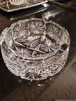 Crystal bowl showing top and side with detailed starburst and geometric cut patterns on a dark countertop.