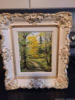 Full frontal view of the framed oil painting showing the forest scene and decorative frame.