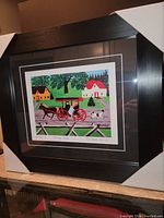 Full view of the professionally framed Maud Lewis print titled "Carriage Ride" with protective corner guards on frame.