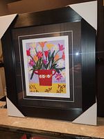 Framed art print by Maud Lewis titled "Flowers in Pot" showing full framed piece with black frame and protective corners.