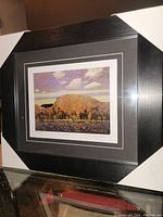 Full view of the professionally framed fine art print showing the black frame, matting, and the print artwork depicting a landscape with autumn foliage mountain and water.