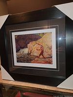Full view of framed art print titled 'The Fisherman' showing the fisherman by the river and large rocks.