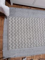 Chevron patterned chevron rug on top of a larger striped rug showing used condition and some stains