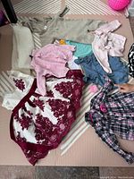 Full view of all mixed baby clothing items arranged on floor