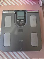 Top view of Omron body composition monitor digital weight scale showing display screen, footpads and control buttons.