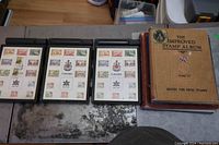 Wide shot showing three black binders with 1967 Canadian stamp set and five older empty stamp albums including 'The Improved Stamp Album'