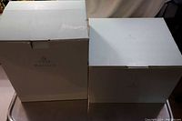 Two large white boxes labeled PartyLite, seen closed side-by-side, showing original packaging for the house lite items.