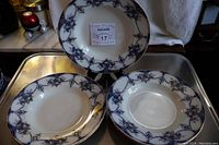 Five flow blue bowls arranged on a tray displaying blue floral and geometric designs on white porcelain.