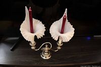 Double candle holder displayed with two red candles inserted. White ruffled Fenton style glass shades on silver-plated base and arms.
